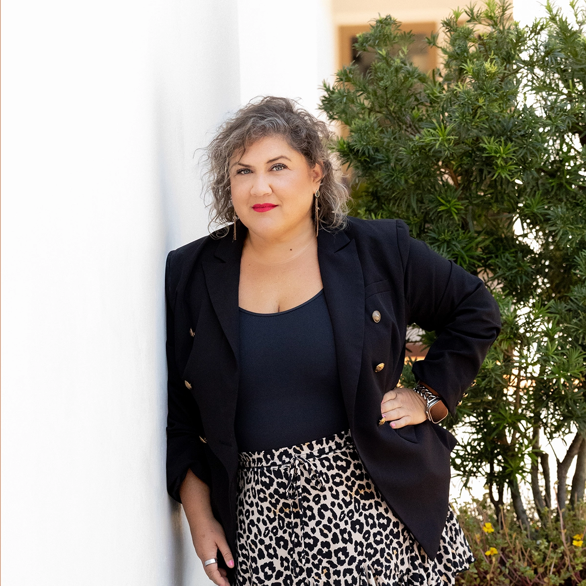 Tiffany Shae, founder of Shine Bright. Speak Truth standing with her hand on hip leaning on white wall